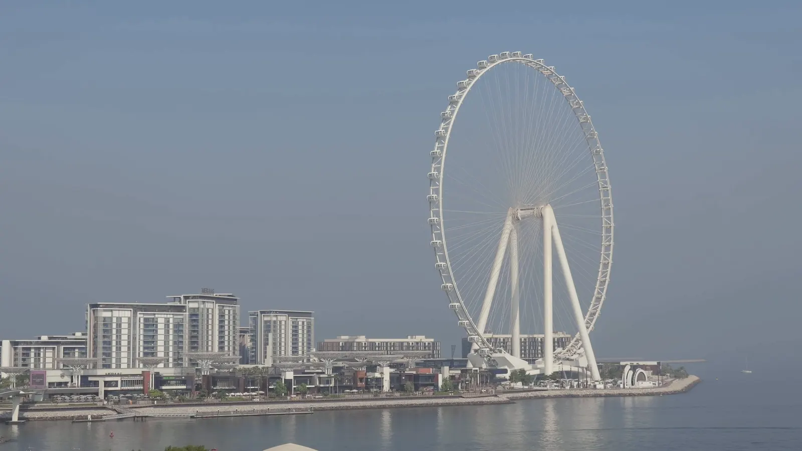 Aerial views of Dubai, opening frame of the hero film. The dome of Louvre Abu Dhabi above calm water